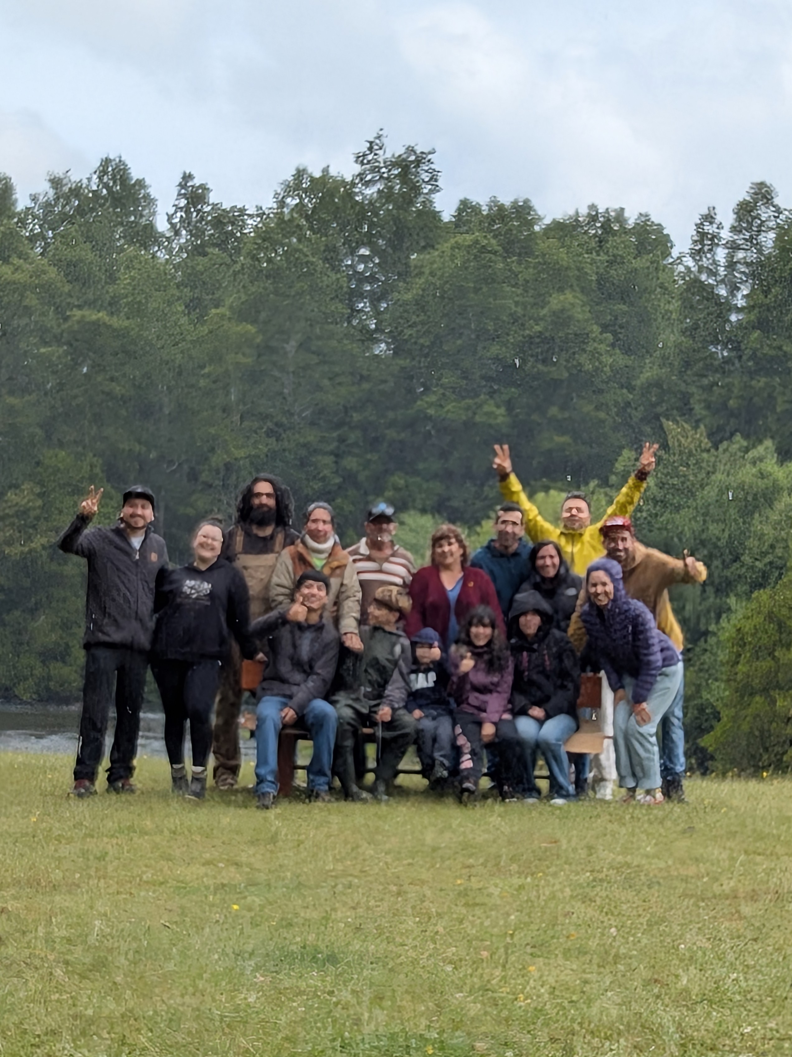 A cheerful group of family and friends posing in the rain in front of a forest