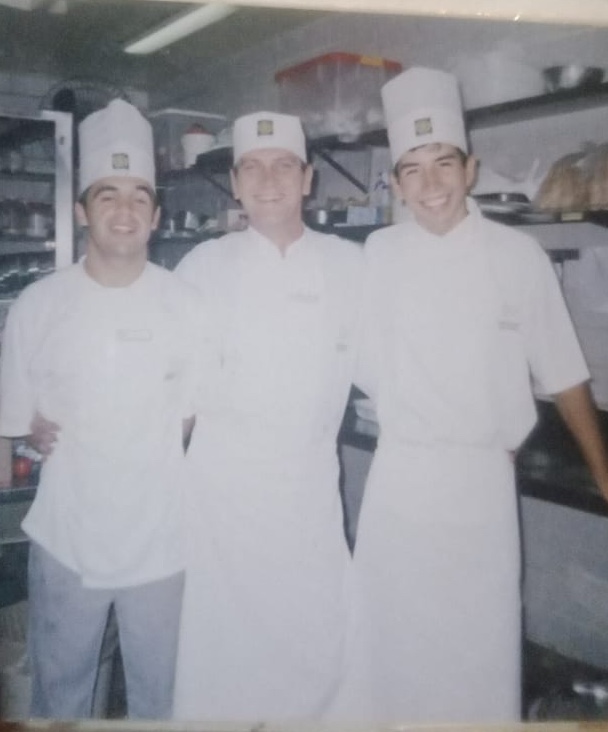 Jose Manuel and two fellow cooks in chef whites and tall hats in a restaurant kitchen