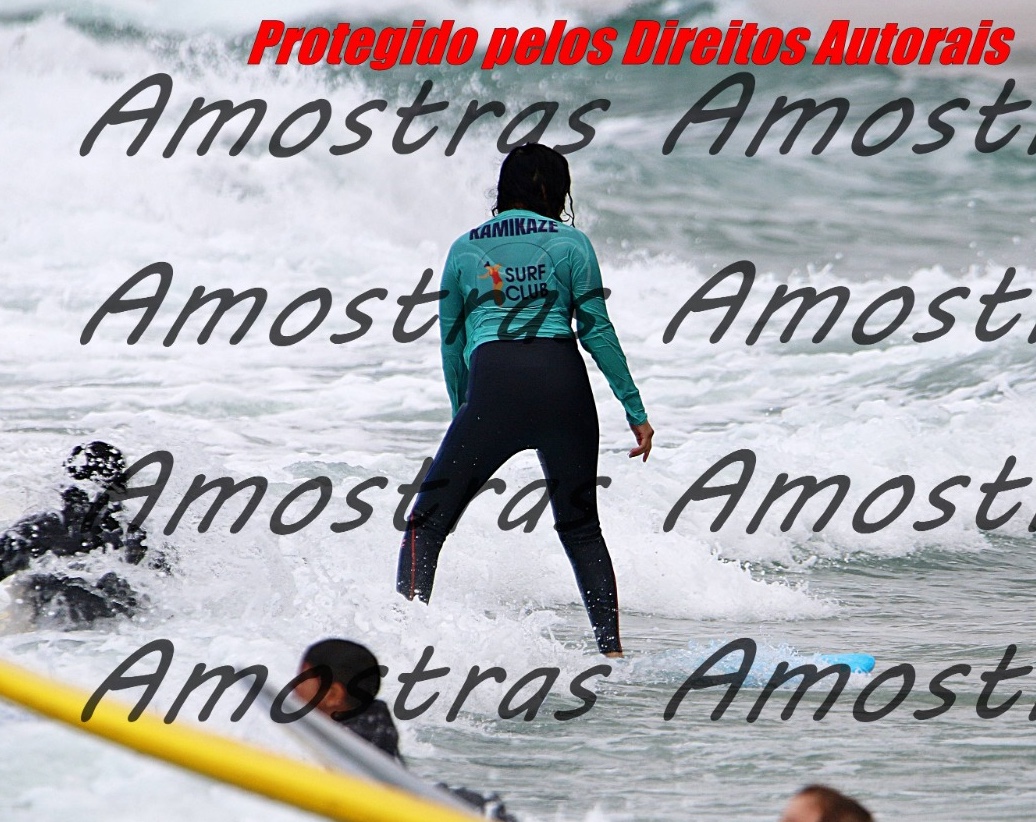 Sabah riding a wave on a surfboard in a teal surf club rash guard