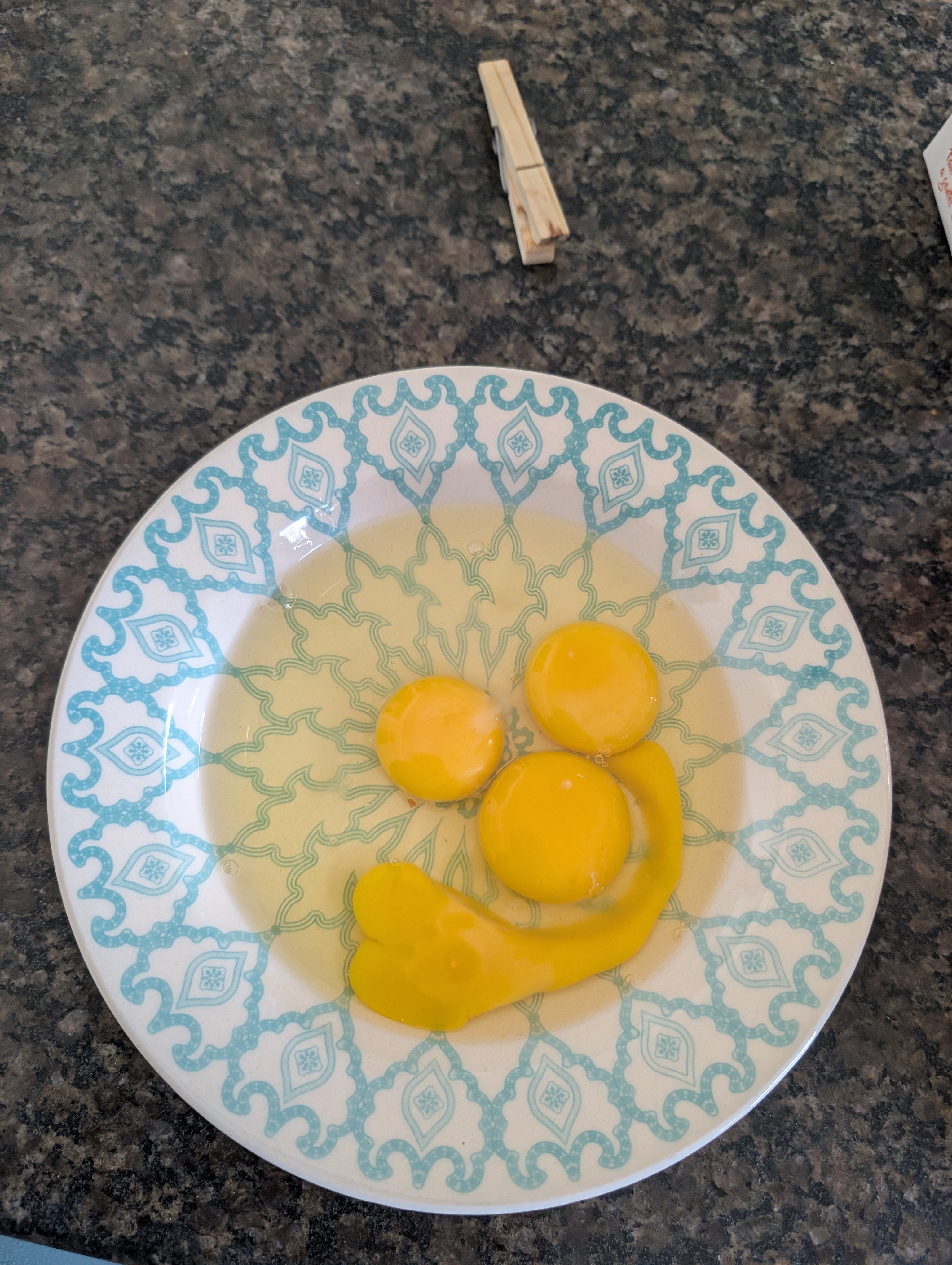 Cracked egg yolks on a blue patterned plate arranged like a smiling face