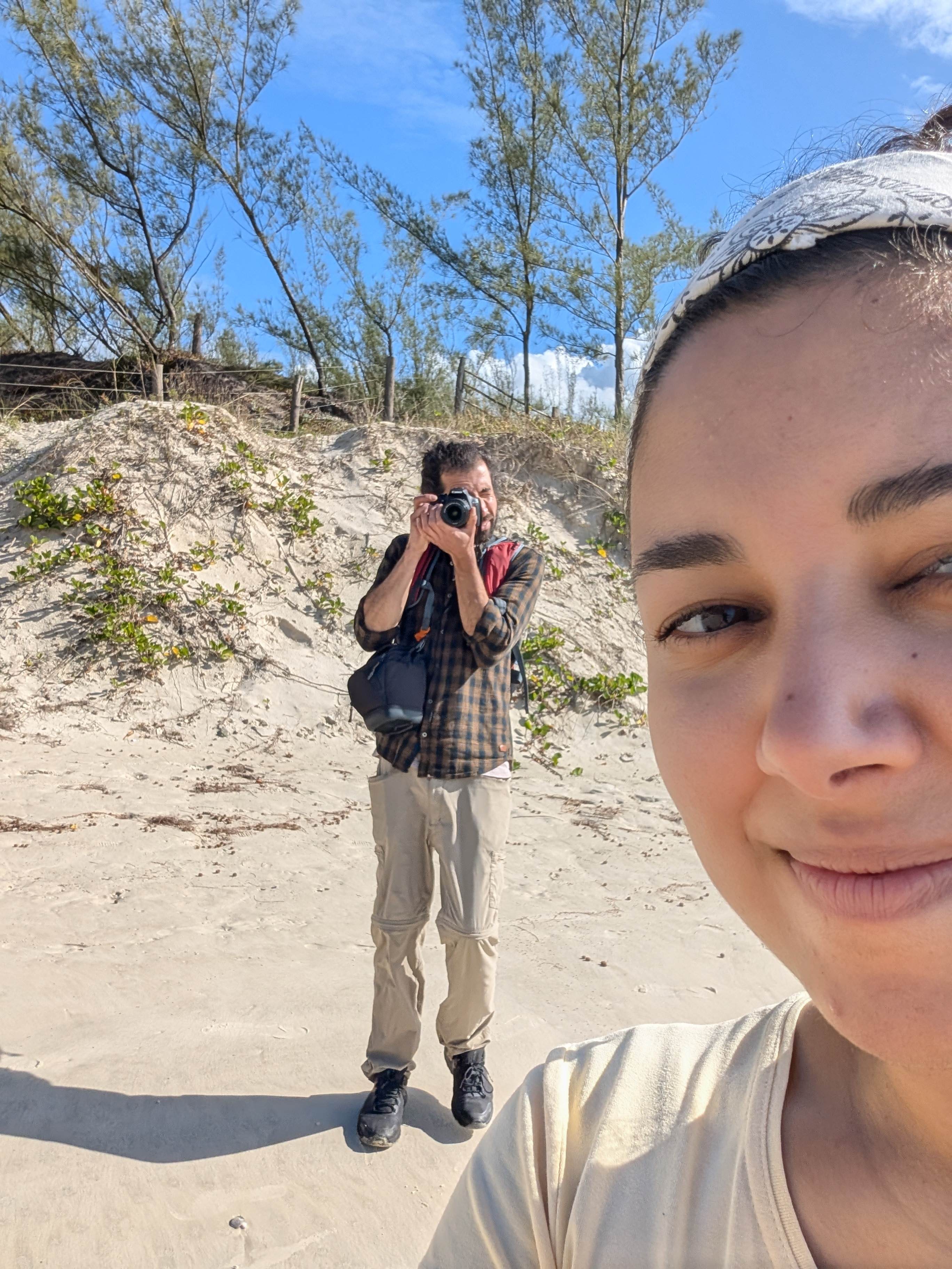 Sabah taking a selfie on a sand dune while Jose Manuel photographs her