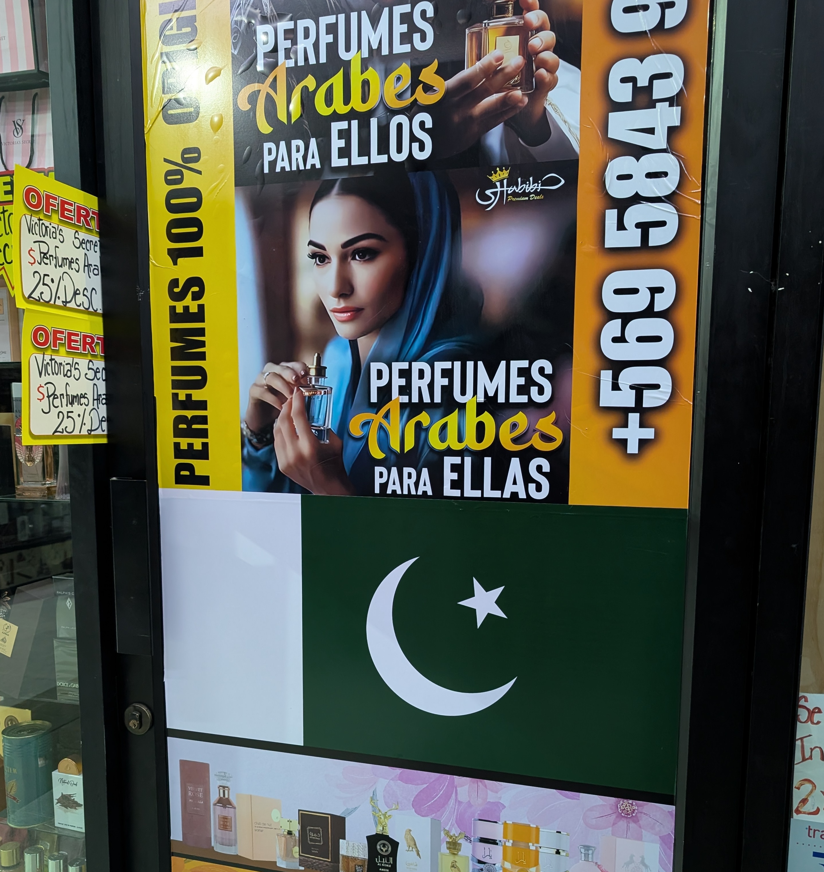 A shop window with Arabic perfume posters and a Pakistani flag