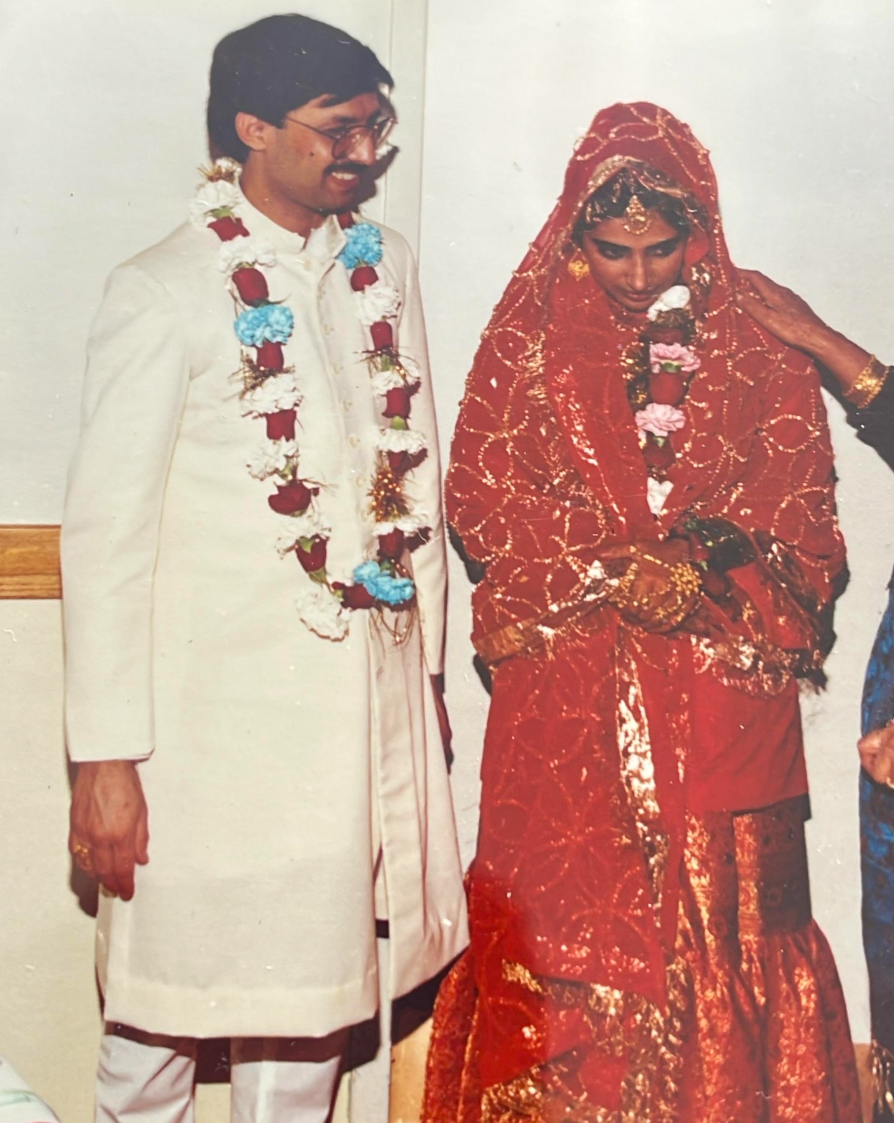 Sabah's parents on their wedding day, her father in a white sherwani and floral garland, her mother in a red and gold dupatta
