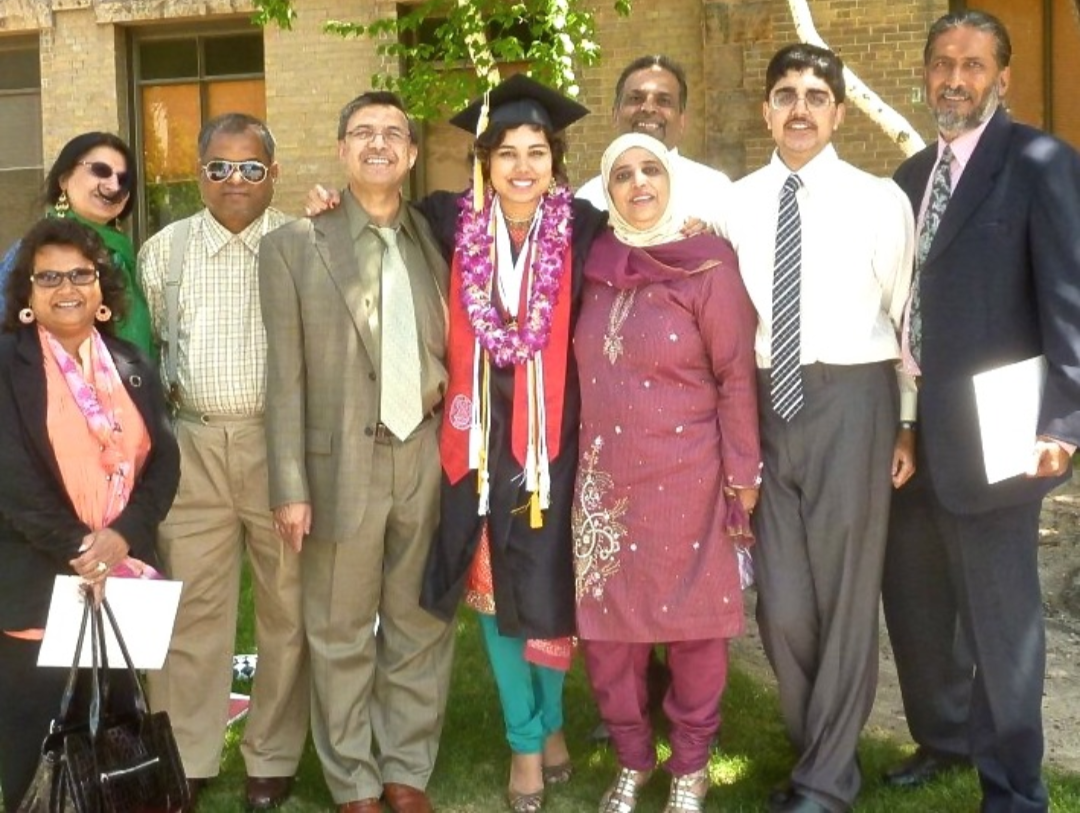 Sabah in her graduation cap, gown and flower lei, surrounded by family